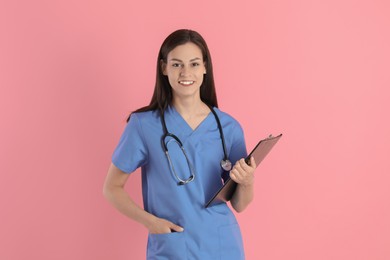 Photo of Smiling nurse with clipboard on pink background