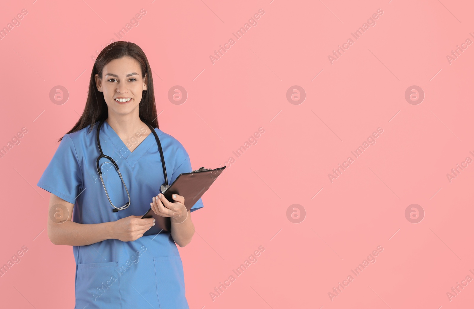 Photo of Smiling nurse with clipboard on pink background. Space for text