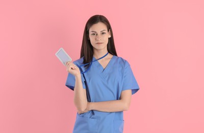 Beautiful nurse with badge on pink background