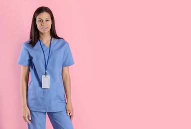 Photo of Smiling nurse with badge on pink background. Space for text