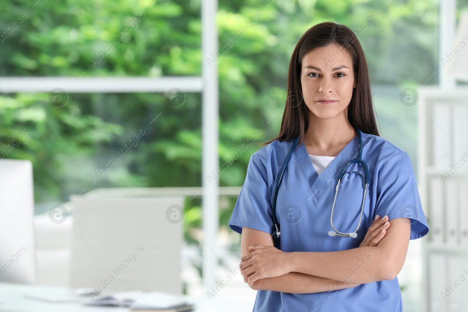 Photo of Beautiful nurse with crossed arms in hospital office. Space for text