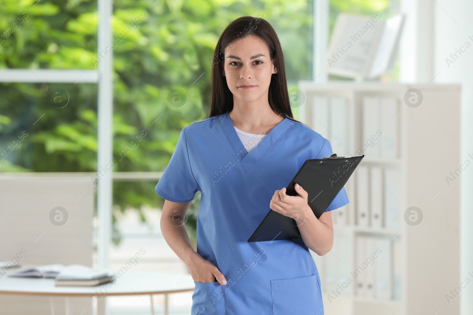 Photo of Beautiful nurse with clipboard in hospital office