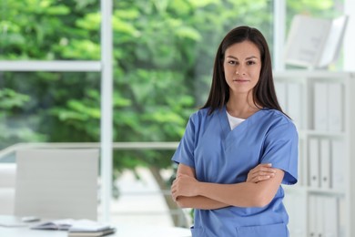 Photo of Beautiful nurse with crossed arms in hospital office. Space for text