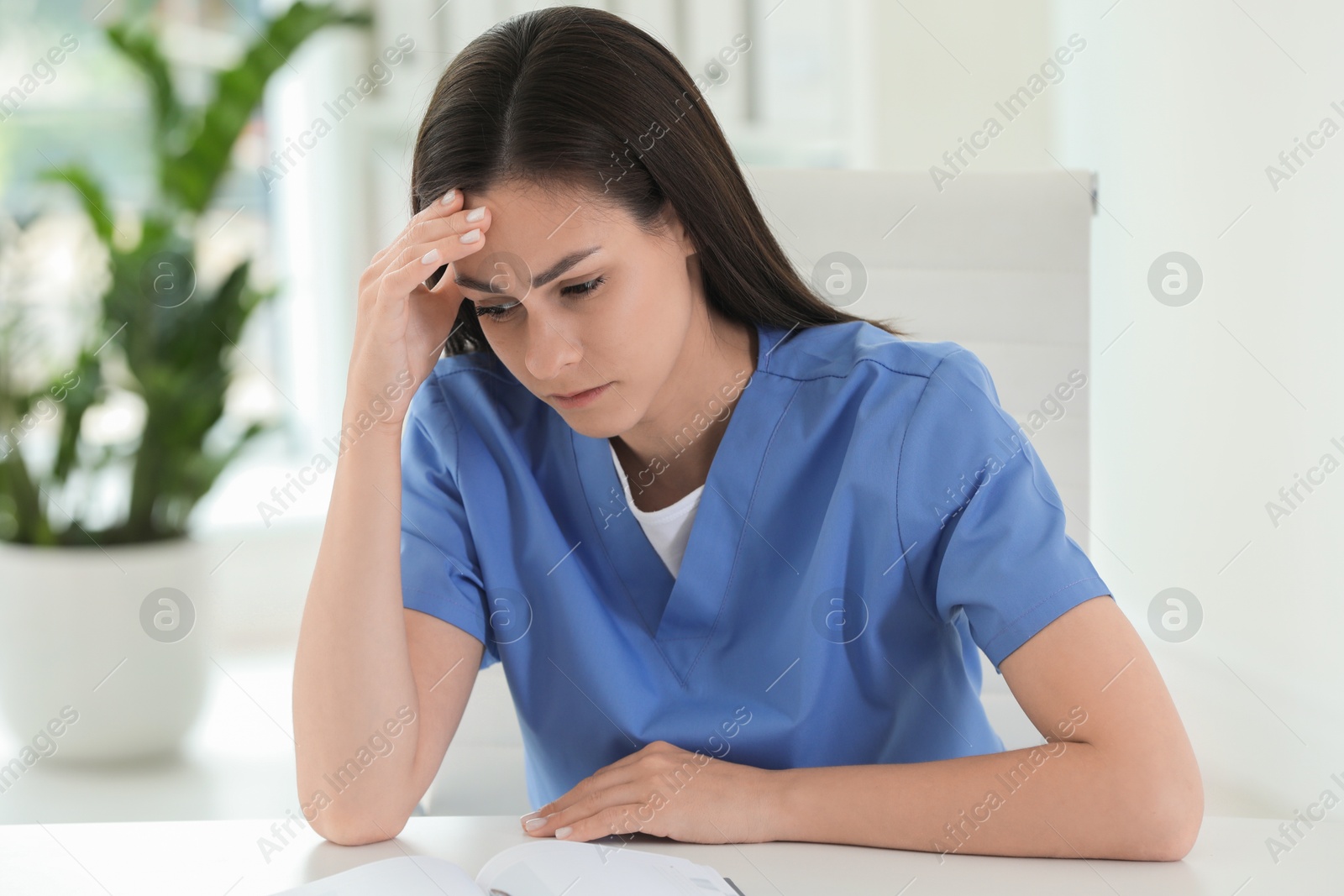 Photo of Tired nurse at table in hospital office