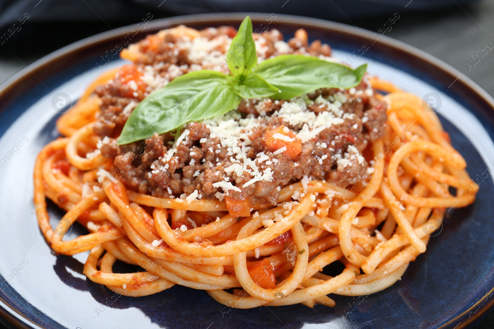 Photo of Delicious pasta bolognese with basil on table, closeup