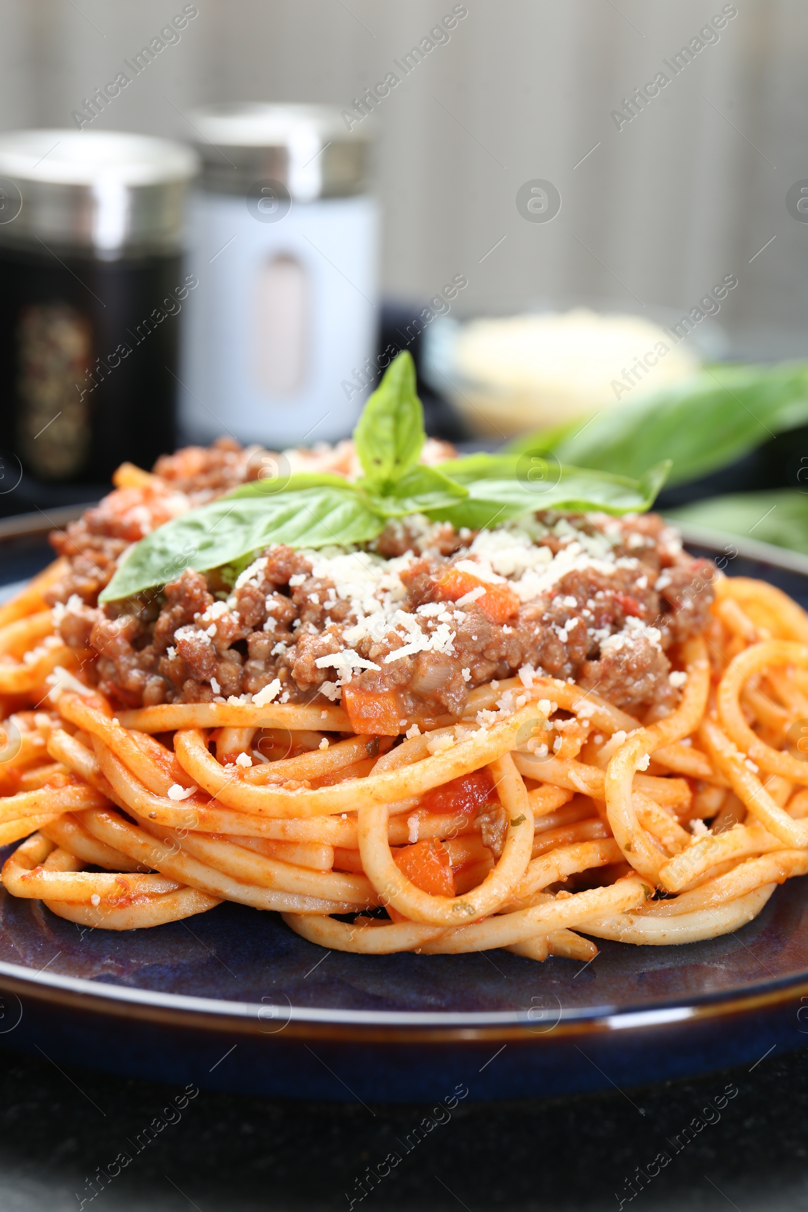 Photo of Delicious pasta bolognese with basil on black table, closeup