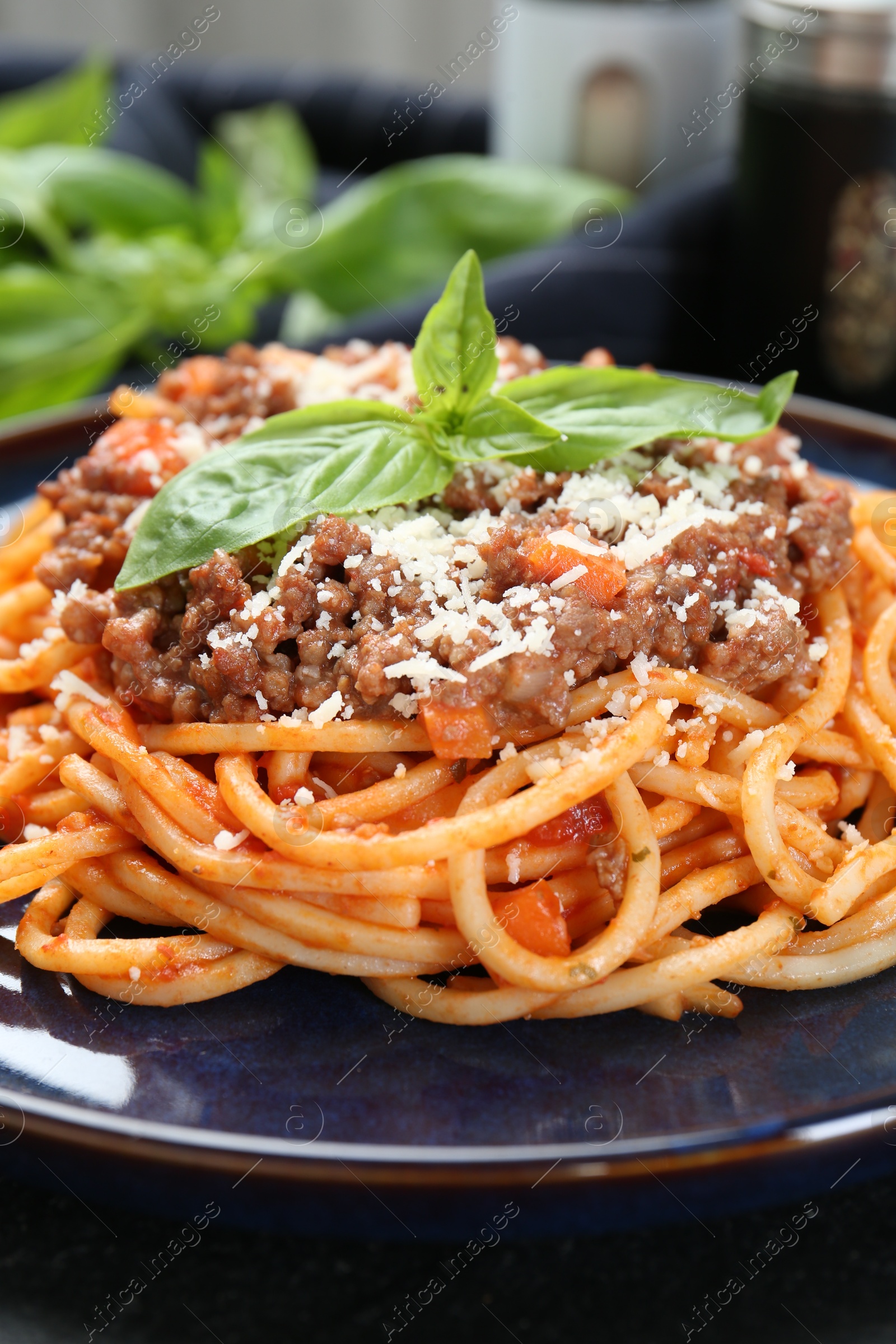 Photo of Delicious pasta bolognese with basil on black table, closeup