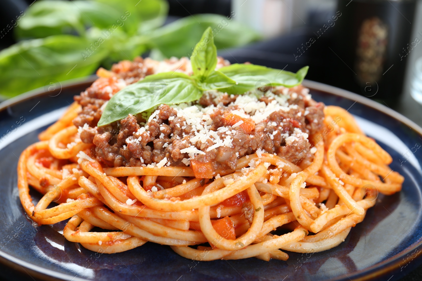 Photo of Delicious pasta bolognese with basil on table, closeup