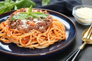 Photo of Delicious pasta bolognese with basil served on black table, closeup