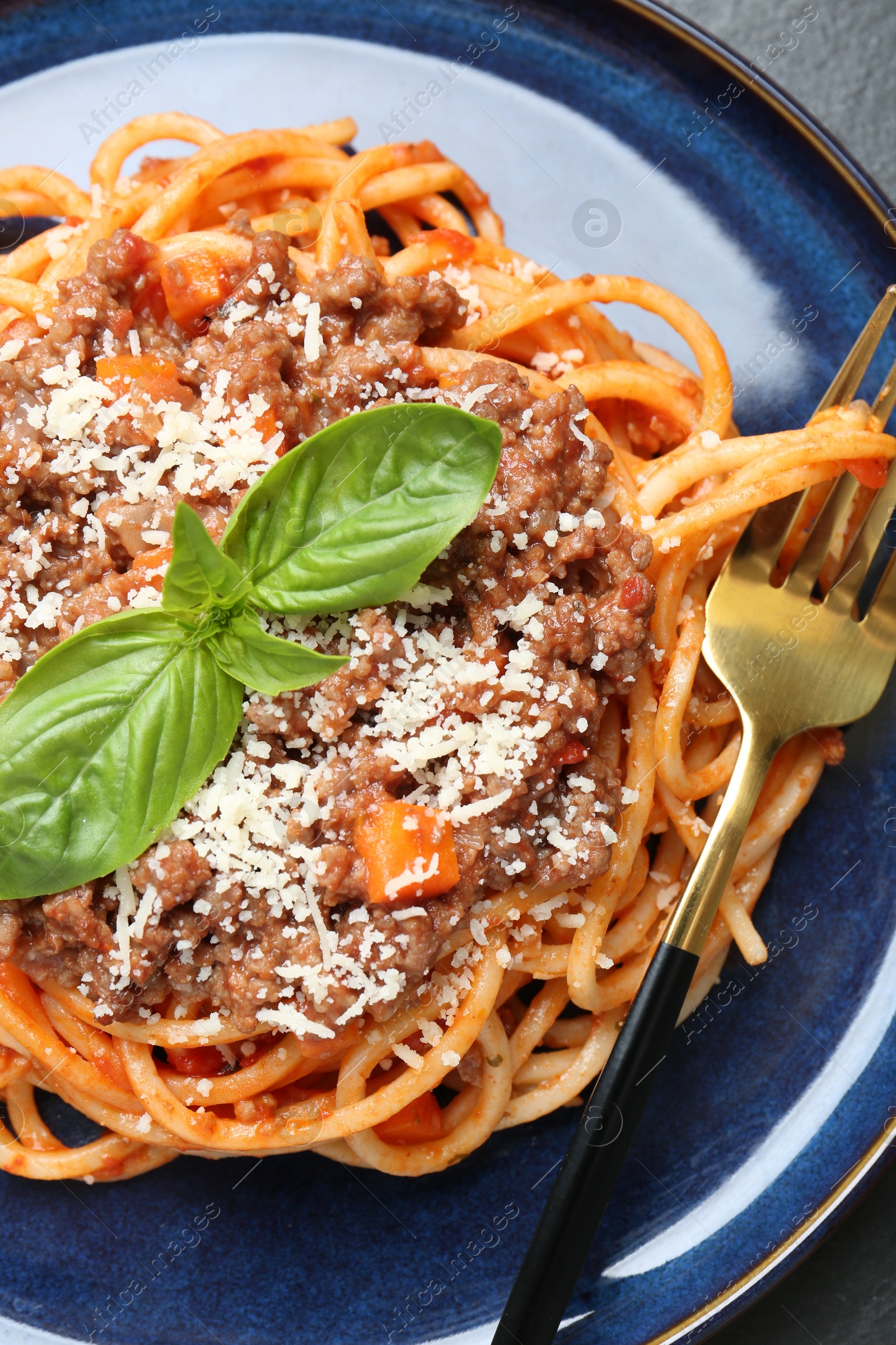 Photo of Delicious pasta bolognese with basil on black table, top view