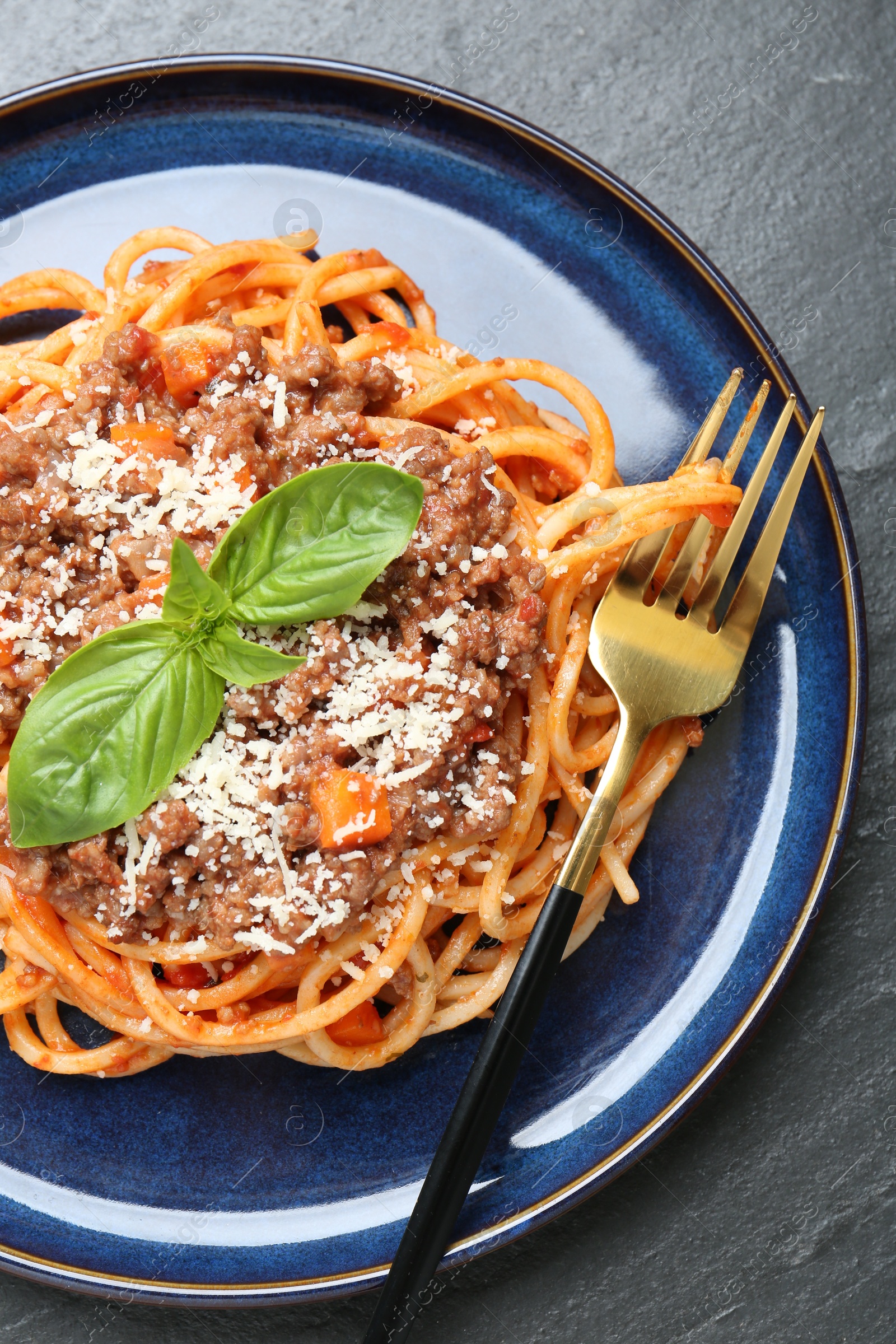 Photo of Delicious pasta bolognese with basil on black table, top view