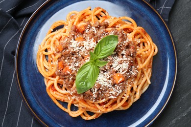 Photo of Delicious pasta bolognese with basil on black table, top view