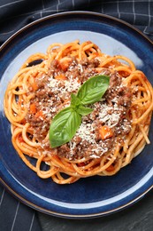 Photo of Delicious pasta bolognese with basil on black table, top view