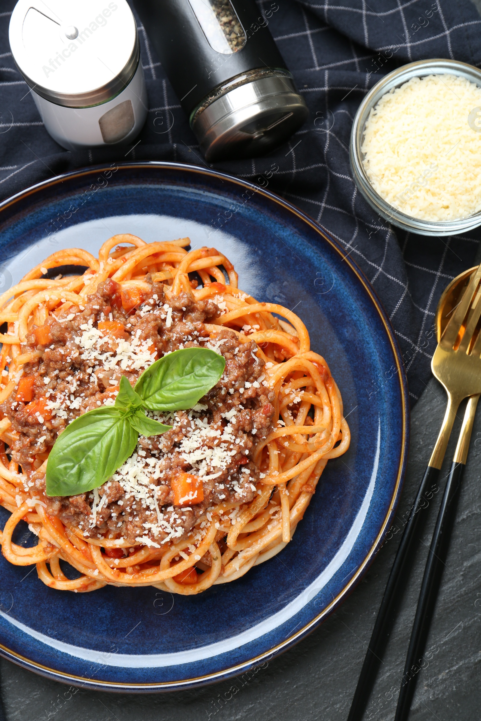 Photo of Delicious pasta bolognese with basil served on black table, flat lay