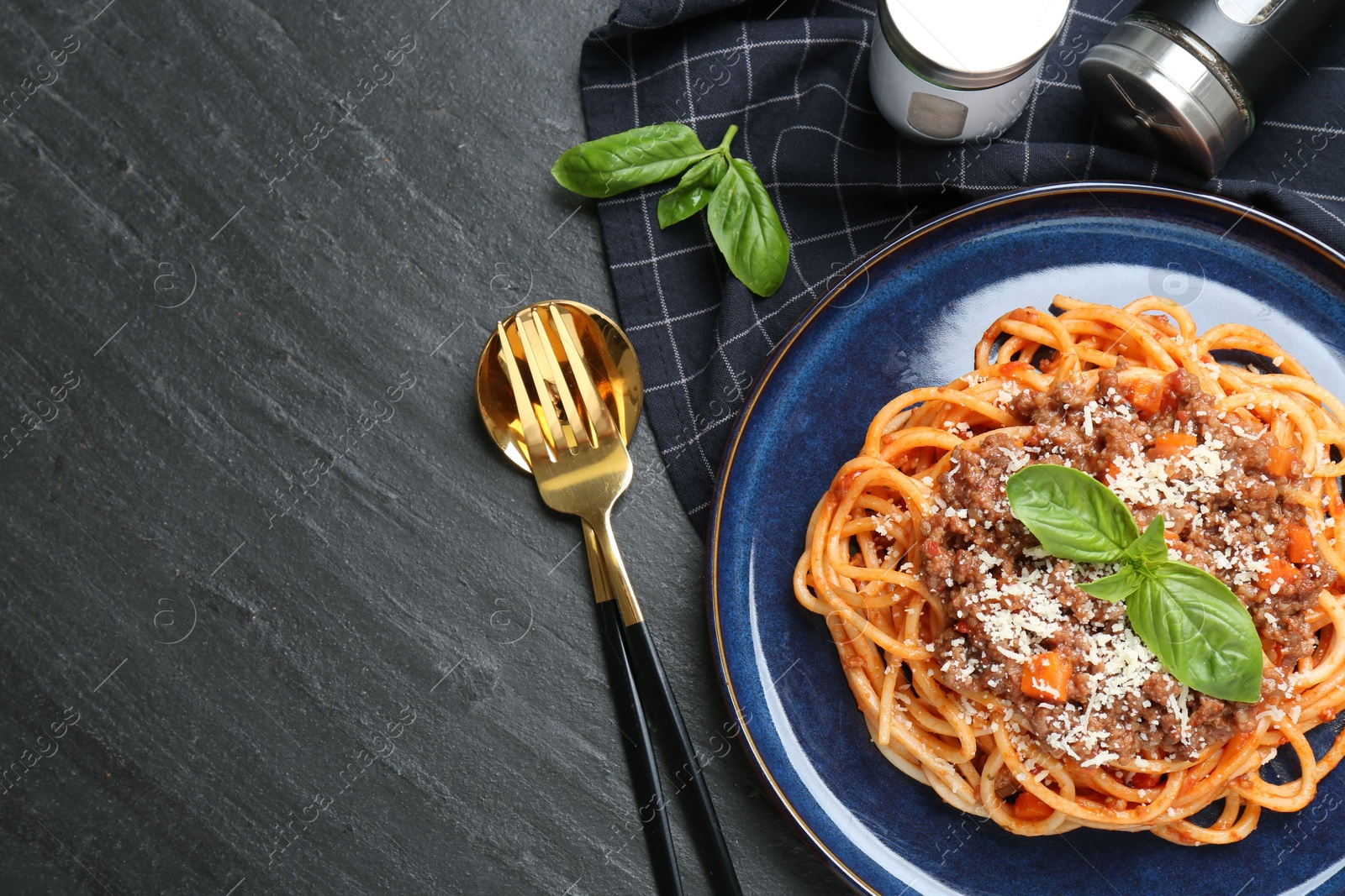 Photo of Delicious pasta bolognese with basil served on black table, flat lay. Space for text