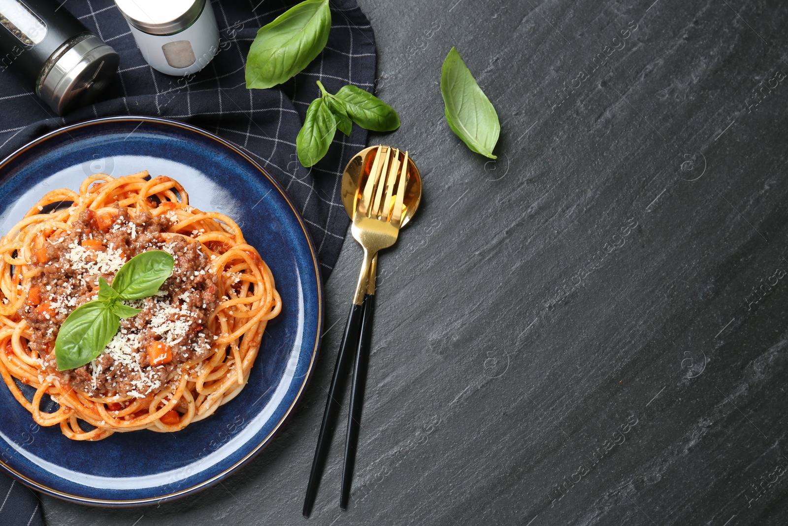 Photo of Delicious pasta bolognese with basil served on black table, flat lay. Space for text