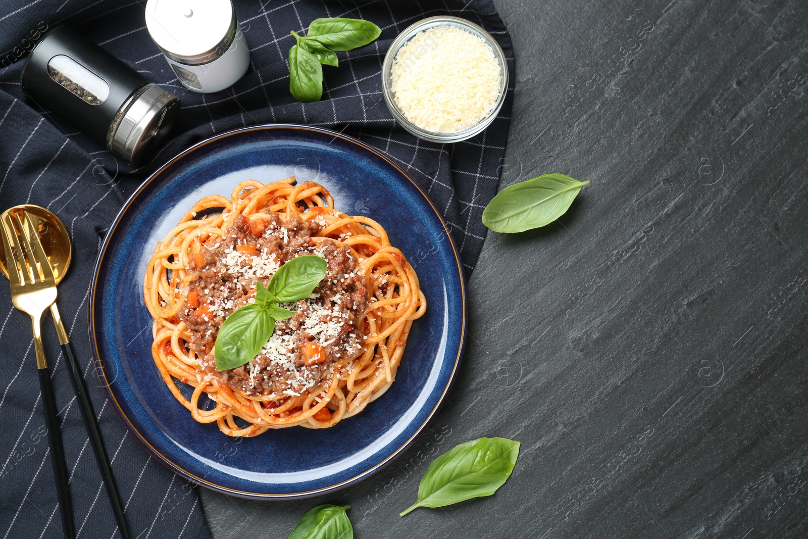 Photo of Delicious pasta bolognese with basil served on black table, flat lay. Space for text