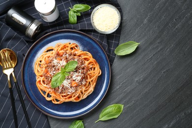 Photo of Delicious pasta bolognese with basil served on black table, flat lay. Space for text