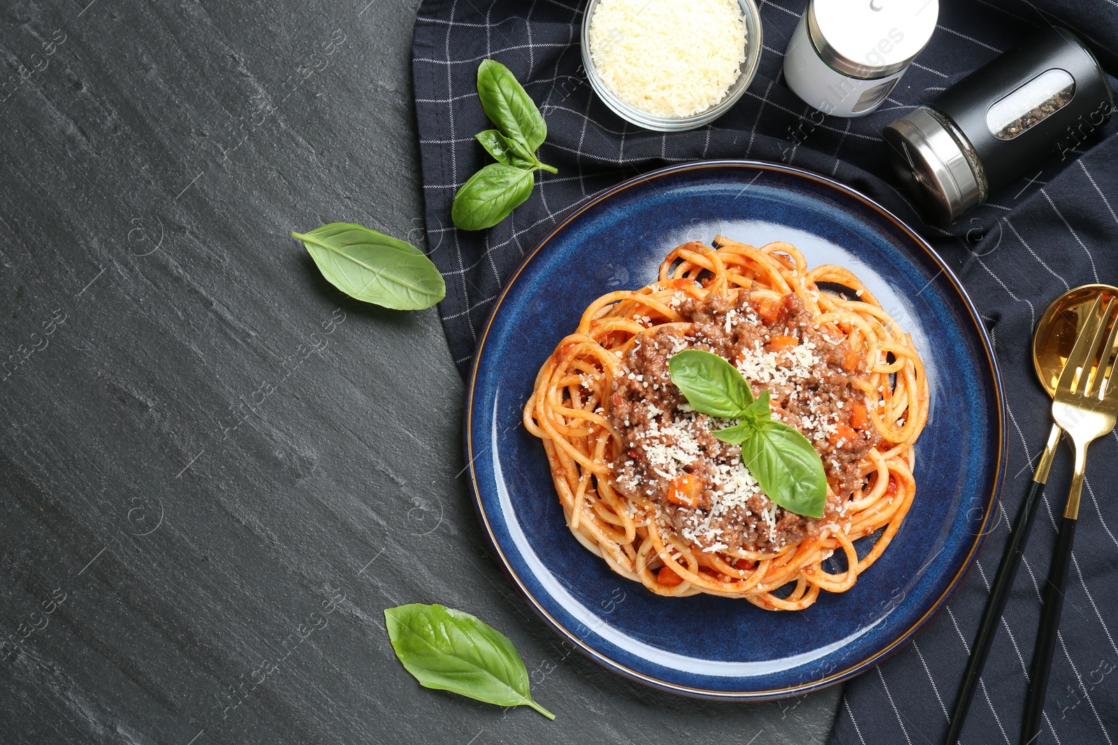 Photo of Delicious pasta bolognese with basil served on black table, flat lay. Space for text