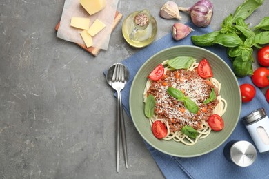 Photo of Delicious pasta bolognese with basil and tomatoes served on grey table, flat lay. Space for text