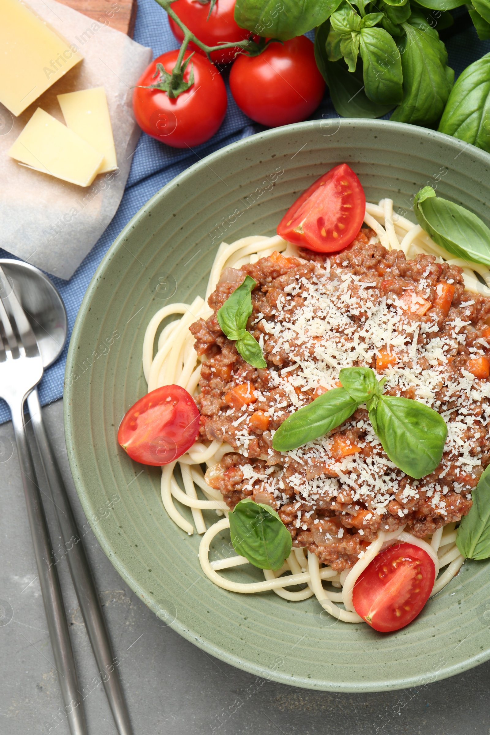 Photo of Delicious pasta bolognese with basil and tomatoes served on grey table, flat lay