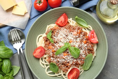 Photo of Delicious pasta bolognese with basil and tomatoes served on grey table, flat lay