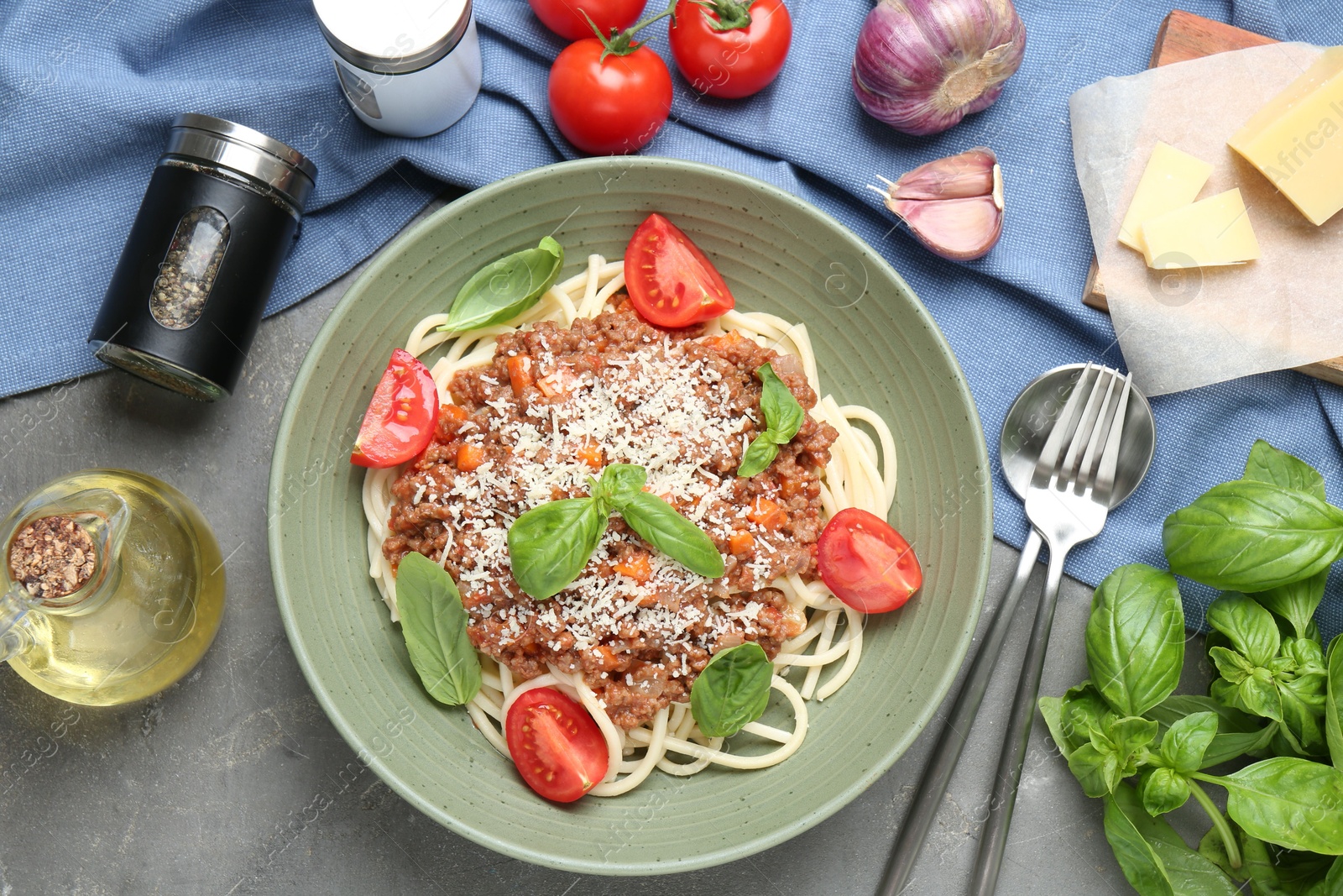 Photo of Delicious pasta bolognese with basil and tomatoes served on grey table, flat lay