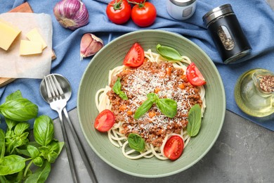 Photo of Delicious pasta bolognese with basil and tomatoes served on grey table, flat lay