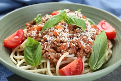 Photo of Delicious pasta bolognese with basil and tomatoes on grey table, closeup