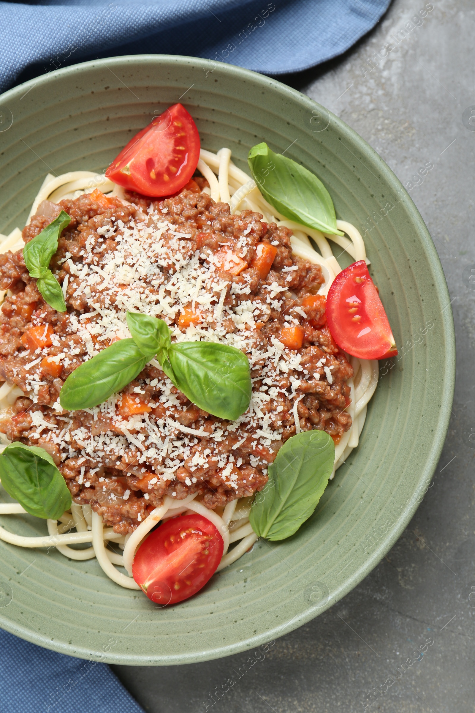 Photo of Delicious pasta bolognese with basil and tomatoes on grey table, top view