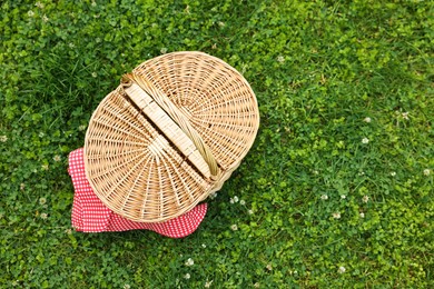 Photo of One picnic wicker basket on green grass, top view. Space for text