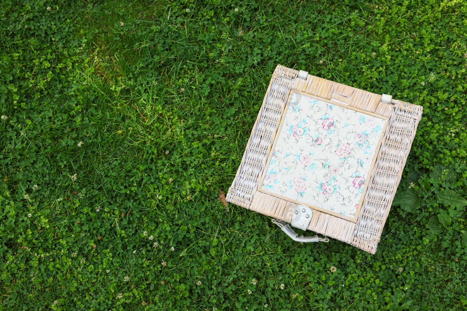 Photo of One picnic wicker basket on green grass, top view. Space for text