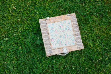 Photo of One picnic wicker basket on green grass, top view