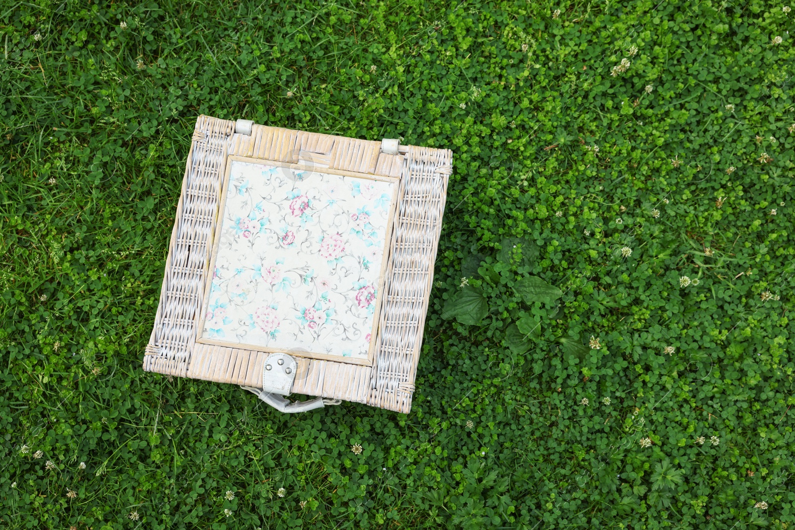 Photo of One picnic wicker basket on green grass, top view. Space for text