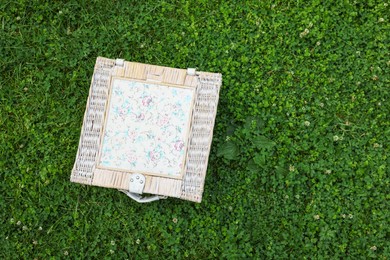 Photo of One picnic wicker basket on green grass, top view. Space for text