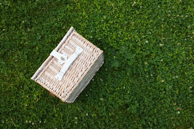 Photo of One picnic wicker basket on green grass, top view. Space for text