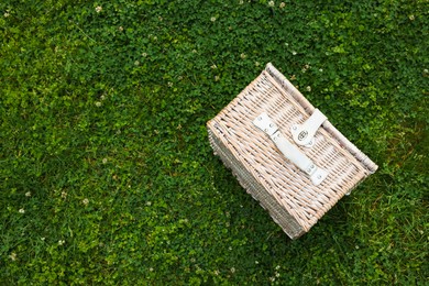 Photo of One picnic wicker basket on green grass, top view. Space for text