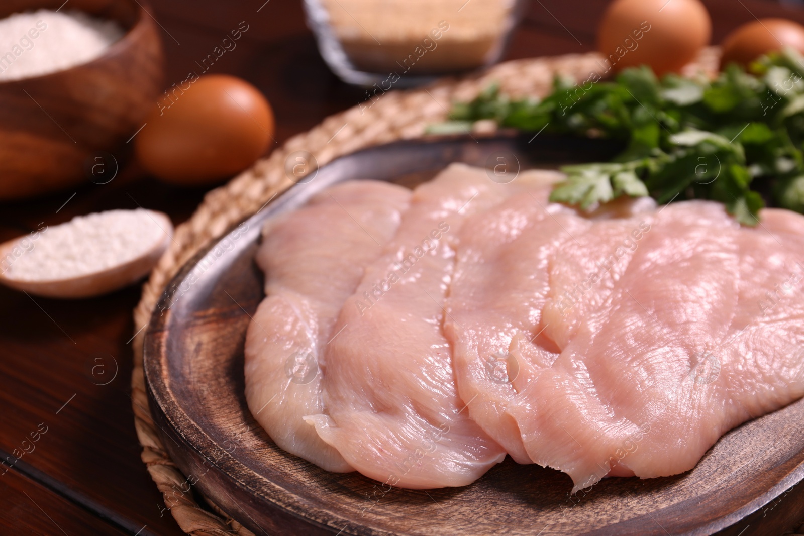 Photo of Making schnitzel. Board with raw meat on wooden table, closeup