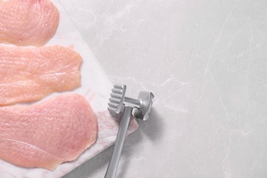 Photo of Making schnitzel. Raw meat chops and tenderizer on light marble table, top view. Space for text