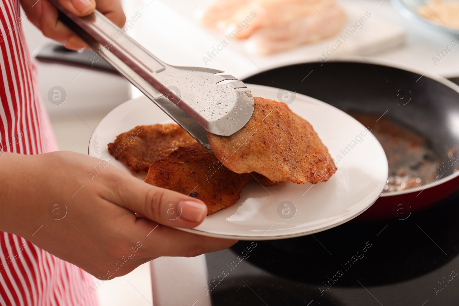 Photo of Woman cooking schnitzels in frying pan on stove, closeup