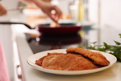 Plate of tasty schnitzels on table in kitchen, closeup