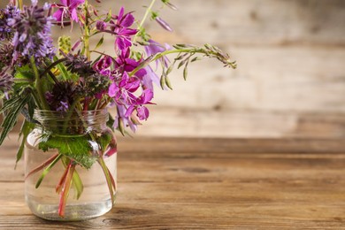 Photo of Bouquet of different healing herbs on wooden table. Space for text