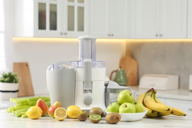 Photo of Modern juicer and fruits on white marble table in kitchen