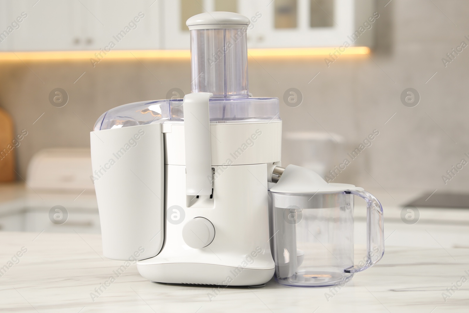 Photo of Modern juicer on white marble table in kitchen