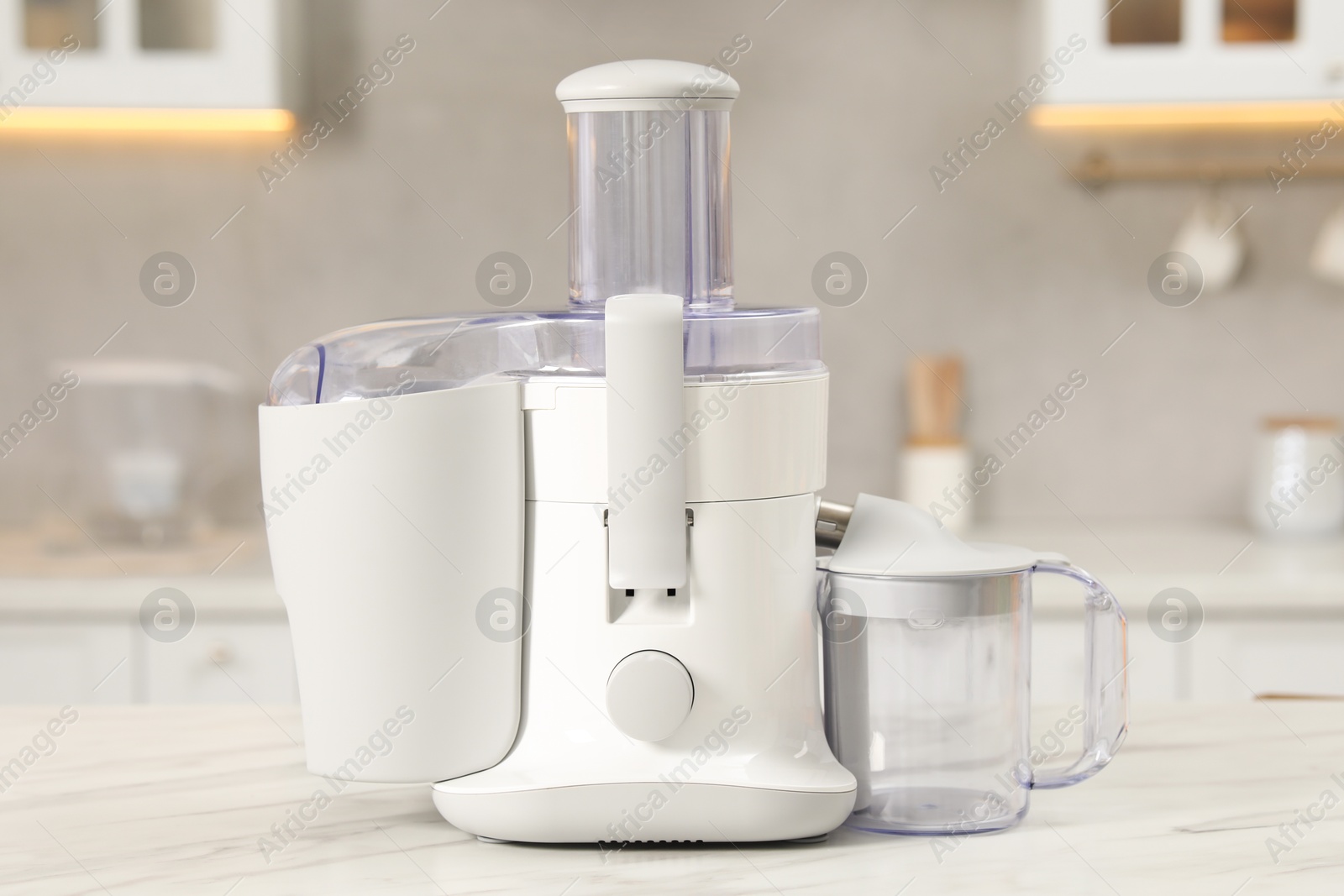 Photo of Modern juicer on white marble table in kitchen