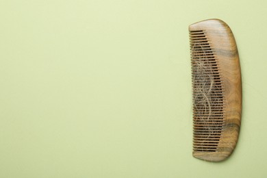 One comb with lost hair on light olive background, top view. Space for text