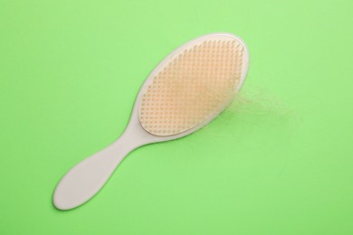 One brush with lost hair on light green background, top view