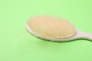 Photo of One brush with lost hair on light green background. Alopecia problem