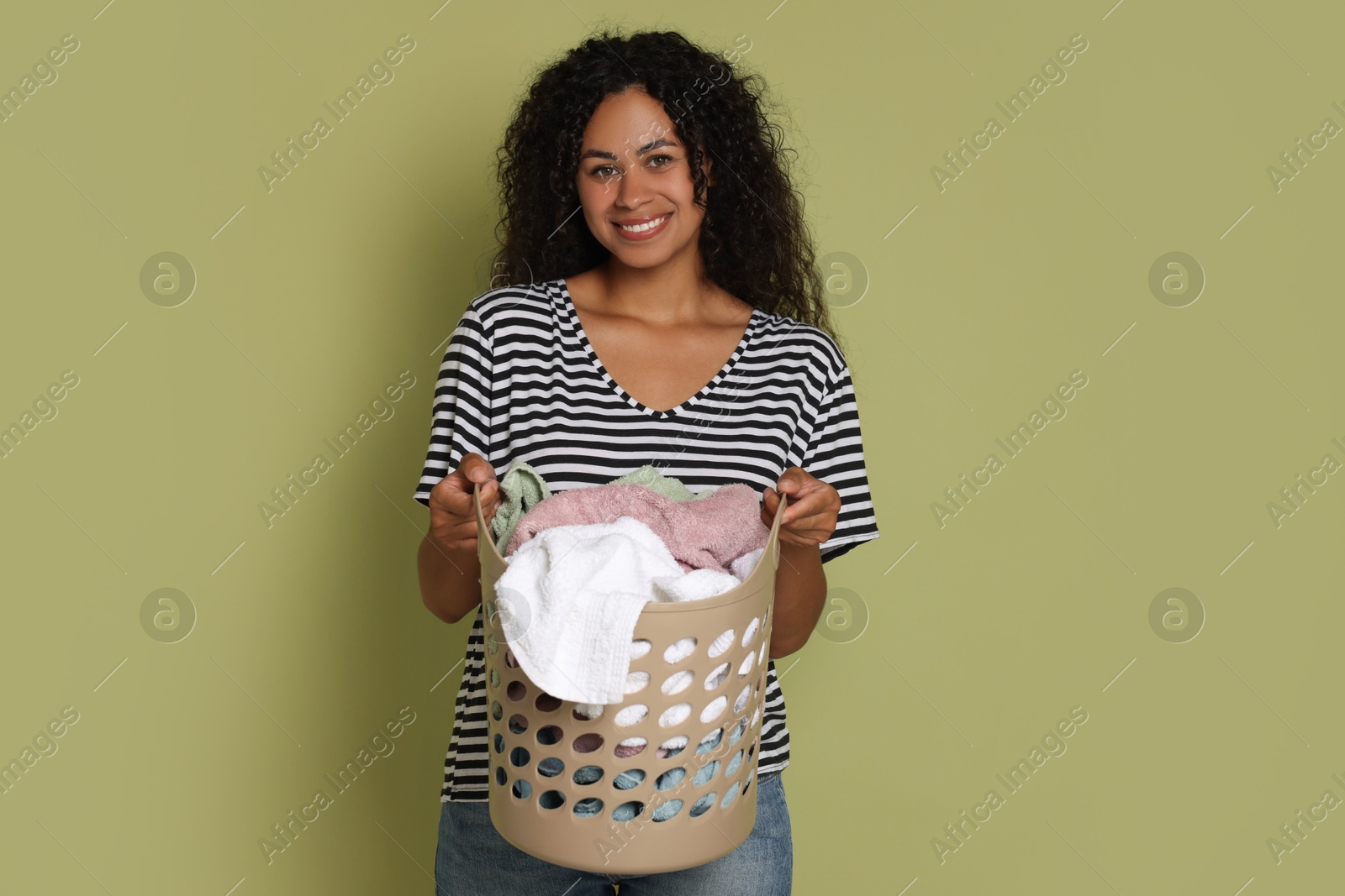 Photo of Happy woman with basket full of laundry on olive background