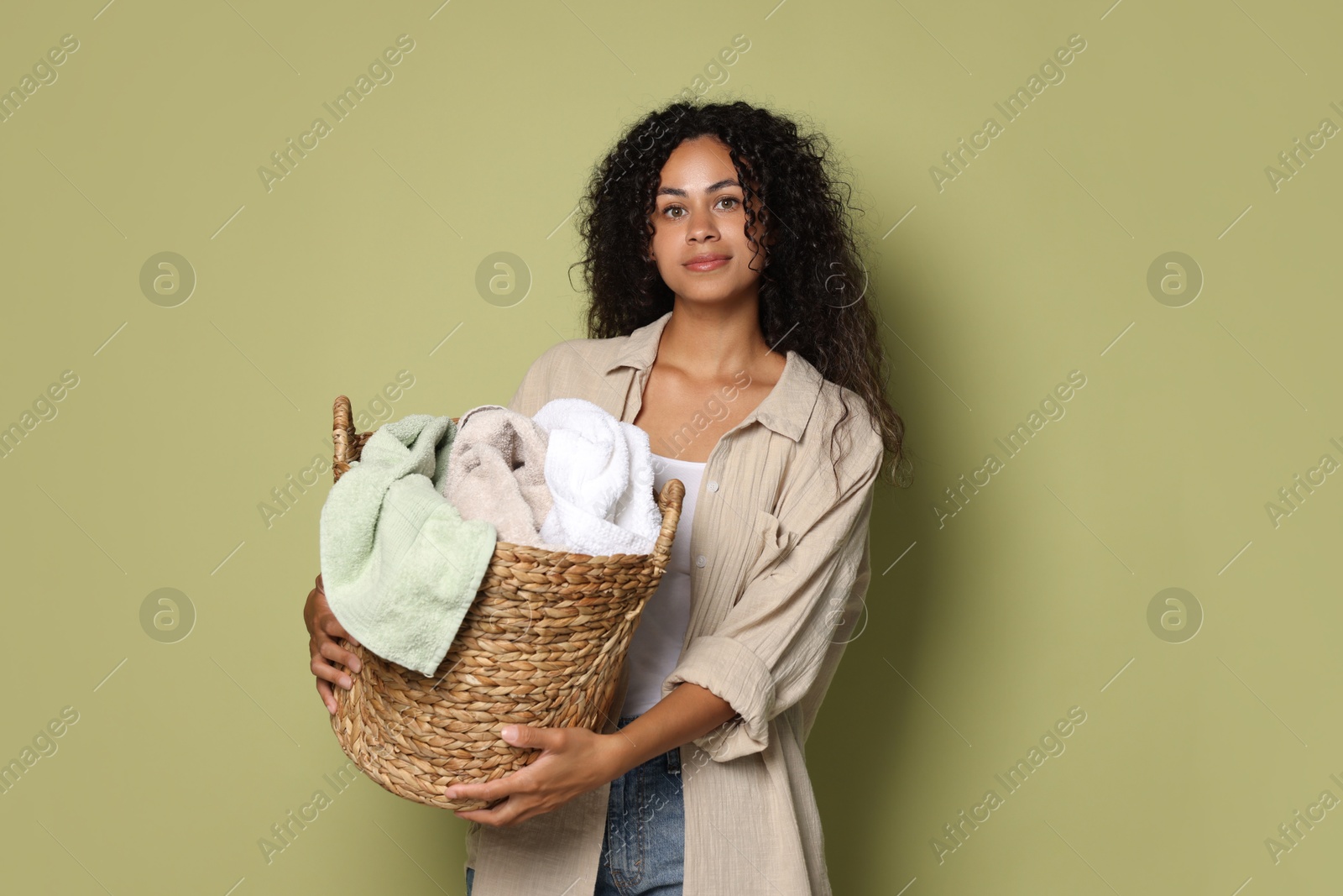 Photo of Woman with basket full of laundry on olive background